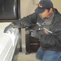 Bed bug inspection technician checking a mattress and bed frame for signs of infestation in Cape Coral, FL