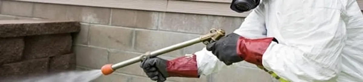 Pest control technician applying exterior insect treatment along a home foundation in Cape Coral, FL