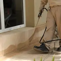 General pest control technician spraying exterior perimeter around a home in Cape Coral, FL