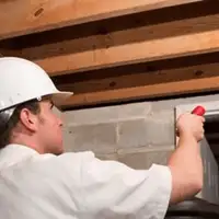 Termite inspection technician checking a basement wall and framing for termite activity in Cape Coral, FL